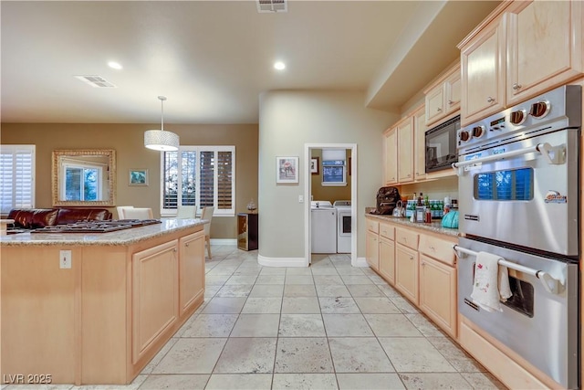 kitchen with plenty of natural light, double oven, black microwave, and washer and clothes dryer