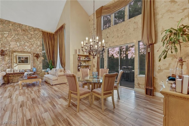 dining space with high vaulted ceiling, light wood finished floors, and a notable chandelier