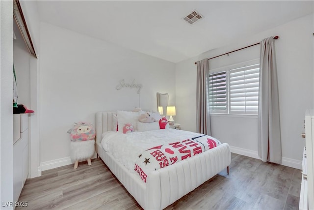 bedroom with light wood finished floors, visible vents, and baseboards