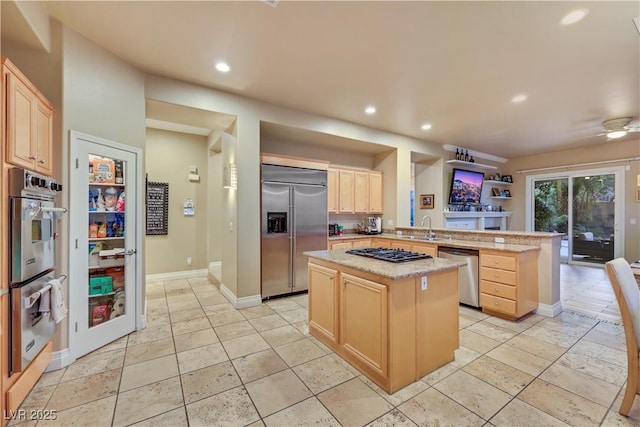 kitchen with light brown cabinets, recessed lighting, a peninsula, a sink, and appliances with stainless steel finishes