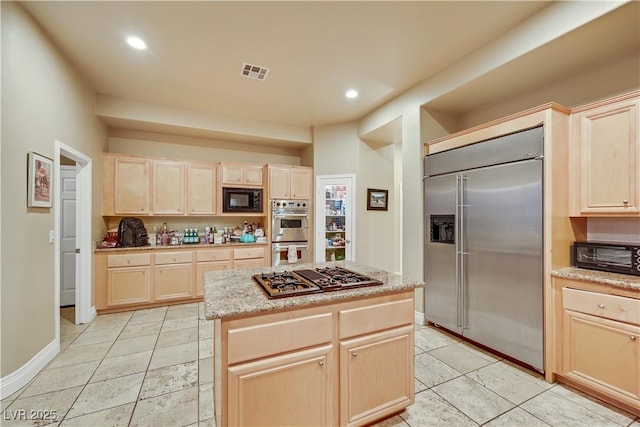 kitchen with built in appliances, light brown cabinets, recessed lighting, visible vents, and a center island