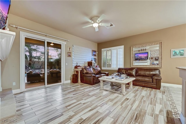 living room featuring baseboards, a ceiling fan, and light wood-style floors