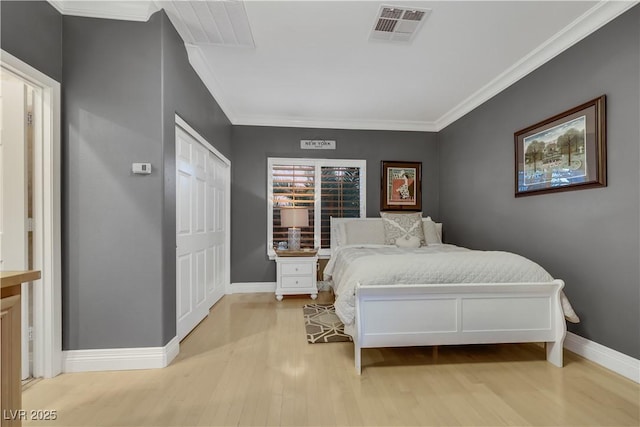 bedroom featuring light wood-type flooring, visible vents, crown molding, and baseboards