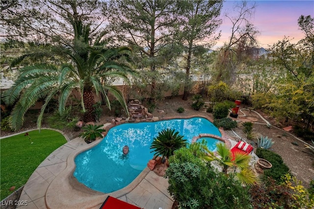 pool at dusk with a pool with connected hot tub