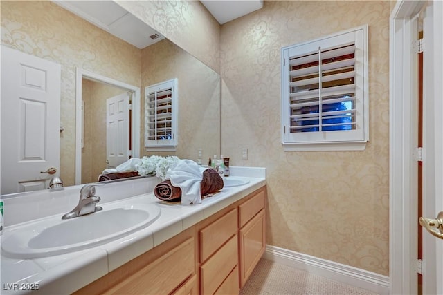 bathroom with a sink, visible vents, baseboards, double vanity, and wallpapered walls