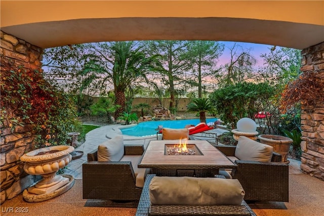 patio terrace at dusk featuring a fenced in pool, an outdoor living space with a fire pit, and a fenced backyard