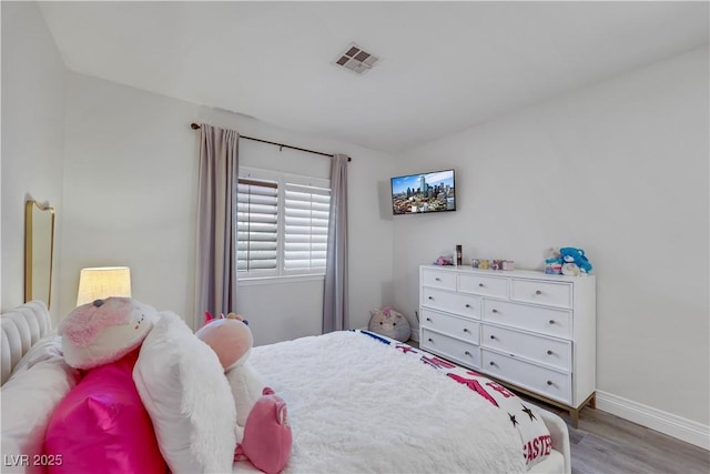 bedroom with visible vents, baseboards, and wood finished floors