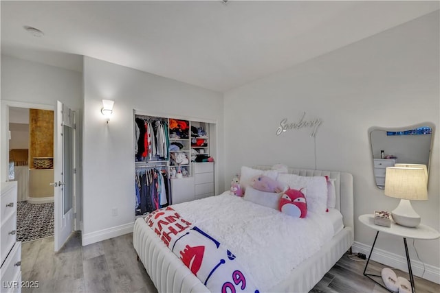 bedroom with a closet, baseboards, and wood finished floors