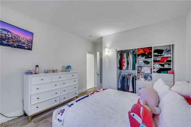 bedroom with a closet, baseboards, and wood finished floors