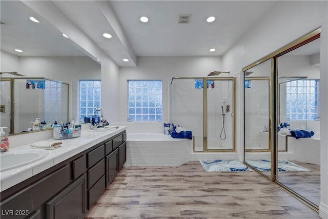 full bath with a garden tub, visible vents, a stall shower, a sink, and wood finished floors