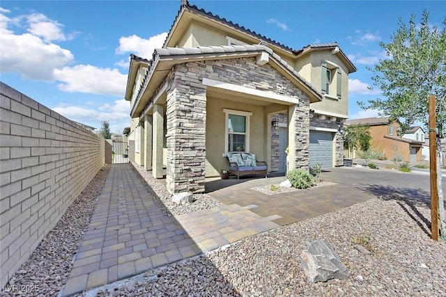 view of front of house featuring aphalt driveway, stone siding, a garage, and stucco siding