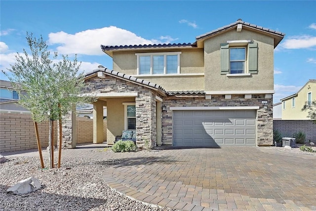 view of front of property featuring stone siding, decorative driveway, fence, and stucco siding