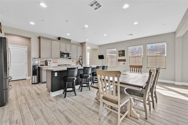 dining space with light wood finished floors, plenty of natural light, visible vents, and recessed lighting