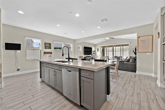 kitchen featuring light countertops, gray cabinetry, stainless steel dishwasher, wood tiled floor, and a sink