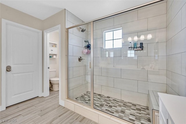 bathroom with toilet, a stall shower, and wood finished floors