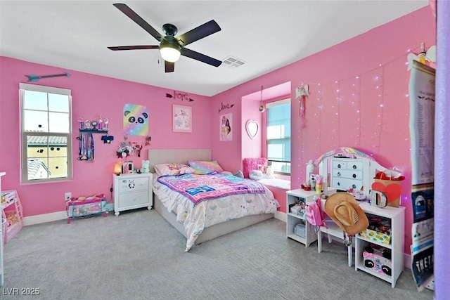 carpeted bedroom with baseboards, multiple windows, visible vents, and a ceiling fan