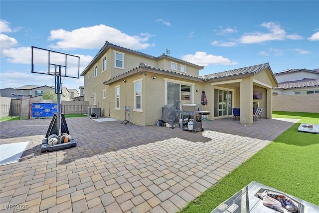 rear view of house with a patio, fence, and stucco siding