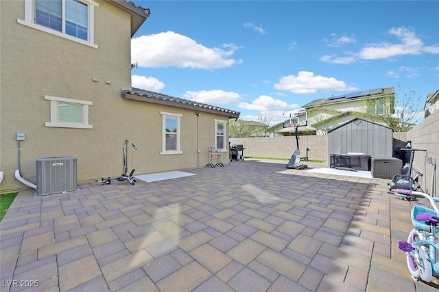 view of patio / terrace featuring a storage shed, a fenced backyard, grilling area, an outdoor structure, and central air condition unit