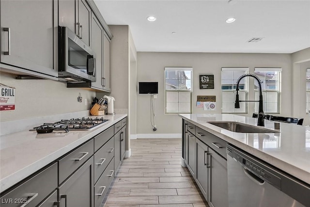 kitchen with visible vents, a sink, stainless steel appliances, gray cabinetry, and a wealth of natural light