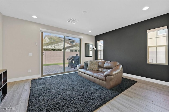 living area featuring light wood-style floors, recessed lighting, visible vents, and baseboards