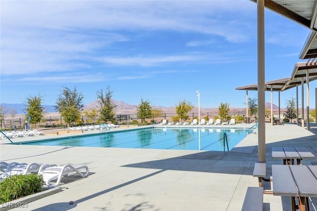 pool with a patio area, fence, and a mountain view