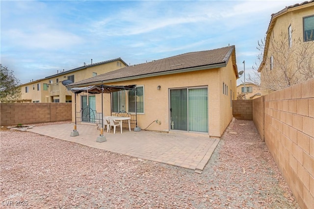 rear view of house with a fenced backyard, a patio, and stucco siding