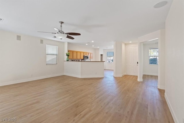 unfurnished living room with a ceiling fan, light wood-style flooring, and baseboards