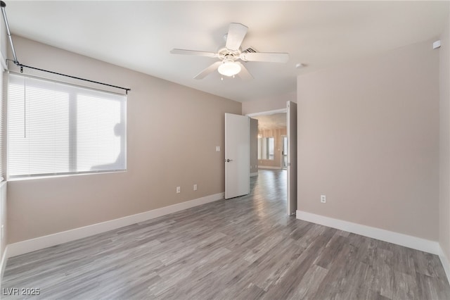 unfurnished room featuring a ceiling fan, baseboards, and wood finished floors