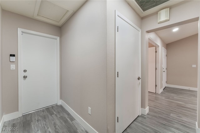 hallway with wood finished floors, attic access, and baseboards