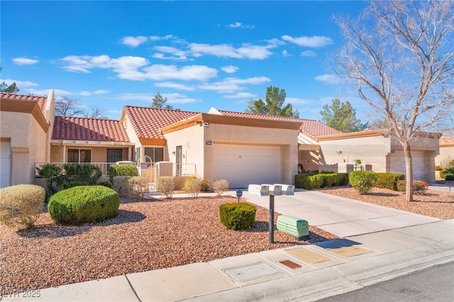 mediterranean / spanish house with stucco siding, a garage, concrete driveway, and a tiled roof