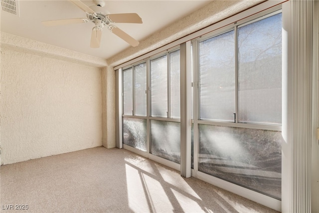 empty room featuring carpet floors, ceiling fan, visible vents, and a textured wall