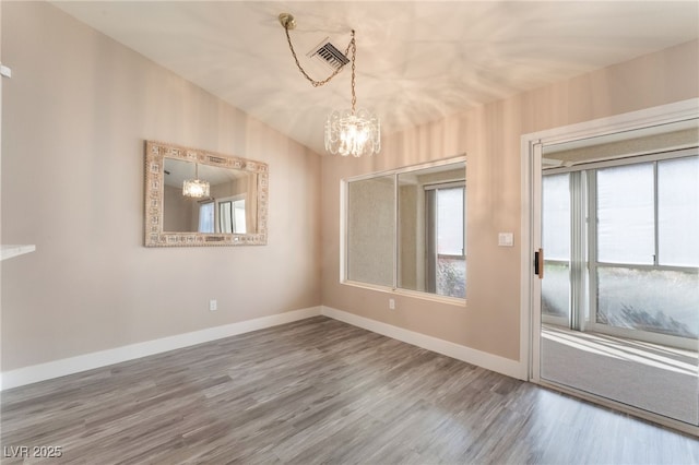 unfurnished dining area featuring a chandelier, visible vents, baseboards, and wood finished floors