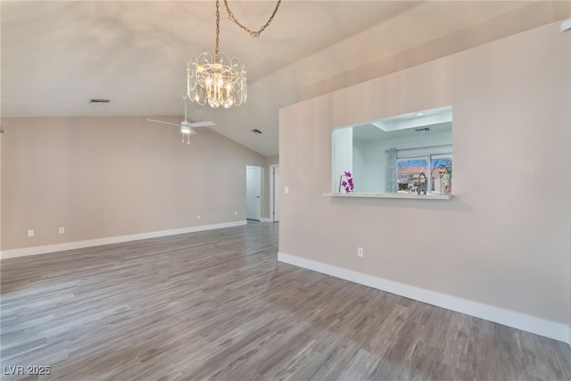 unfurnished room with visible vents, vaulted ceiling, wood finished floors, baseboards, and ceiling fan with notable chandelier