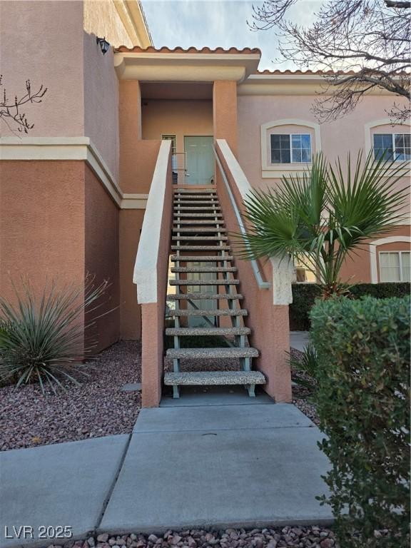 view of exterior entry featuring a tiled roof and stucco siding