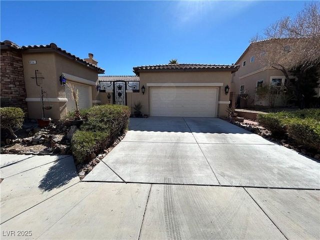 mediterranean / spanish-style home with an attached garage, a tile roof, concrete driveway, and stucco siding