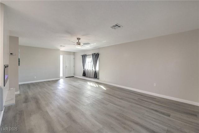 unfurnished room with a ceiling fan, visible vents, baseboards, and wood finished floors