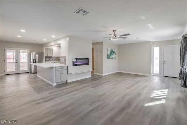 interior space with stainless steel fridge, visible vents, light wood-style flooring, light countertops, and french doors