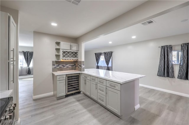 kitchen with gray cabinets, light wood-type flooring, beverage cooler, and a peninsula