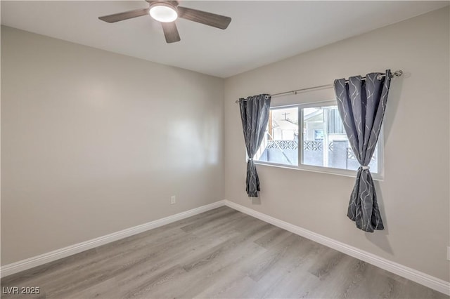 spare room featuring wood finished floors, a ceiling fan, and baseboards