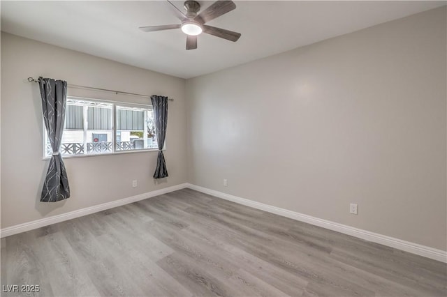 spare room featuring ceiling fan, baseboards, and wood finished floors