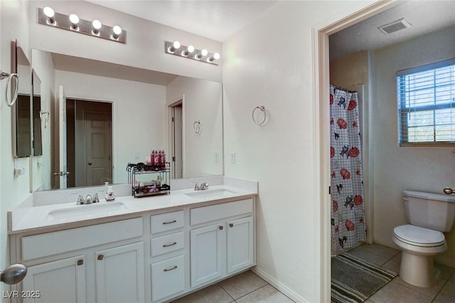 bathroom with double vanity, a sink, toilet, and tile patterned floors