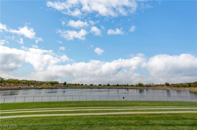 view of property's community featuring a water view, a lawn, and fence