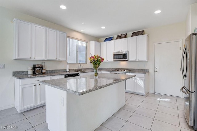 kitchen featuring light stone counters, light tile patterned floors, stainless steel appliances, white cabinets, and a sink