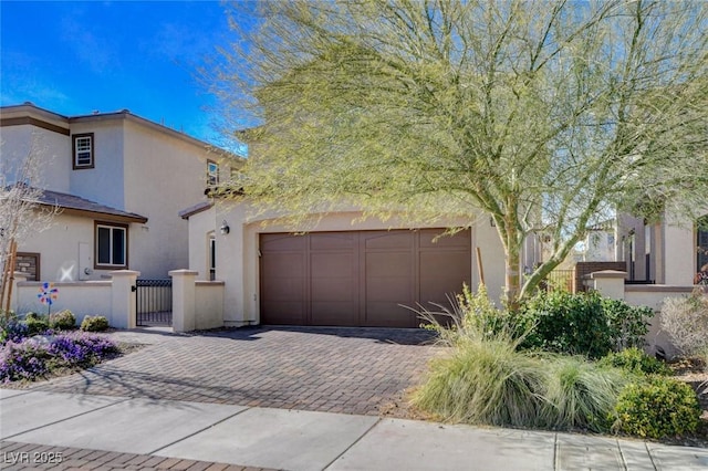 view of front of property featuring a fenced front yard, a garage, decorative driveway, a gate, and stucco siding