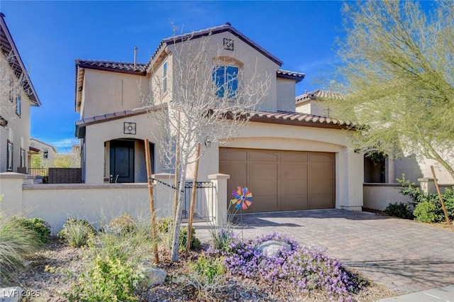 mediterranean / spanish-style home with decorative driveway, a tile roof, fence, and stucco siding