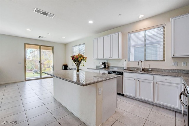 kitchen with stone counters, a sink, visible vents, a center island, and dishwasher