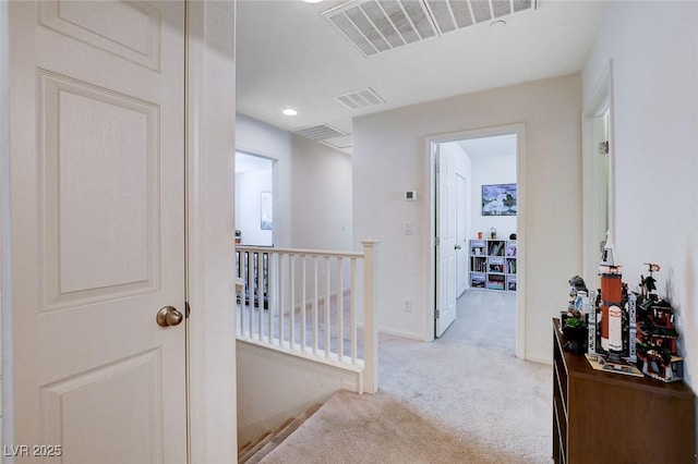 hallway with light carpet, baseboards, visible vents, and an upstairs landing