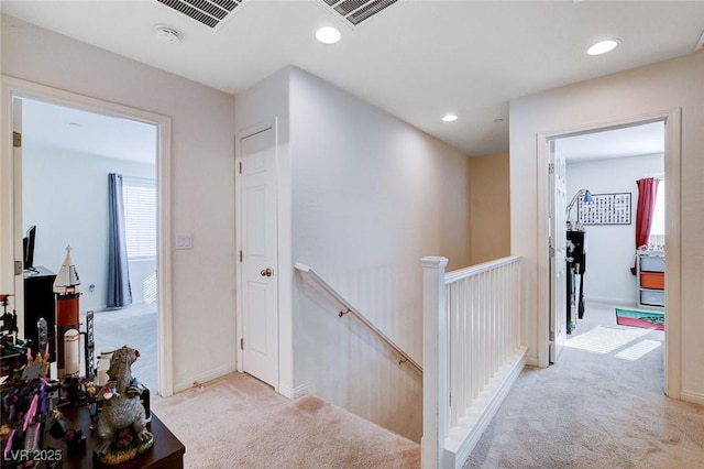 hallway with light carpet, recessed lighting, visible vents, and an upstairs landing