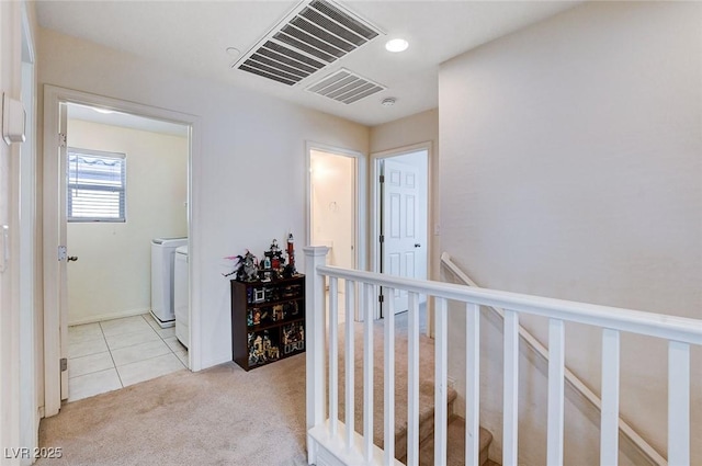 hall with visible vents, tile patterned floors, an upstairs landing, carpet floors, and separate washer and dryer