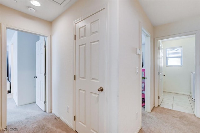 corridor with light carpet, baseboards, and light tile patterned flooring